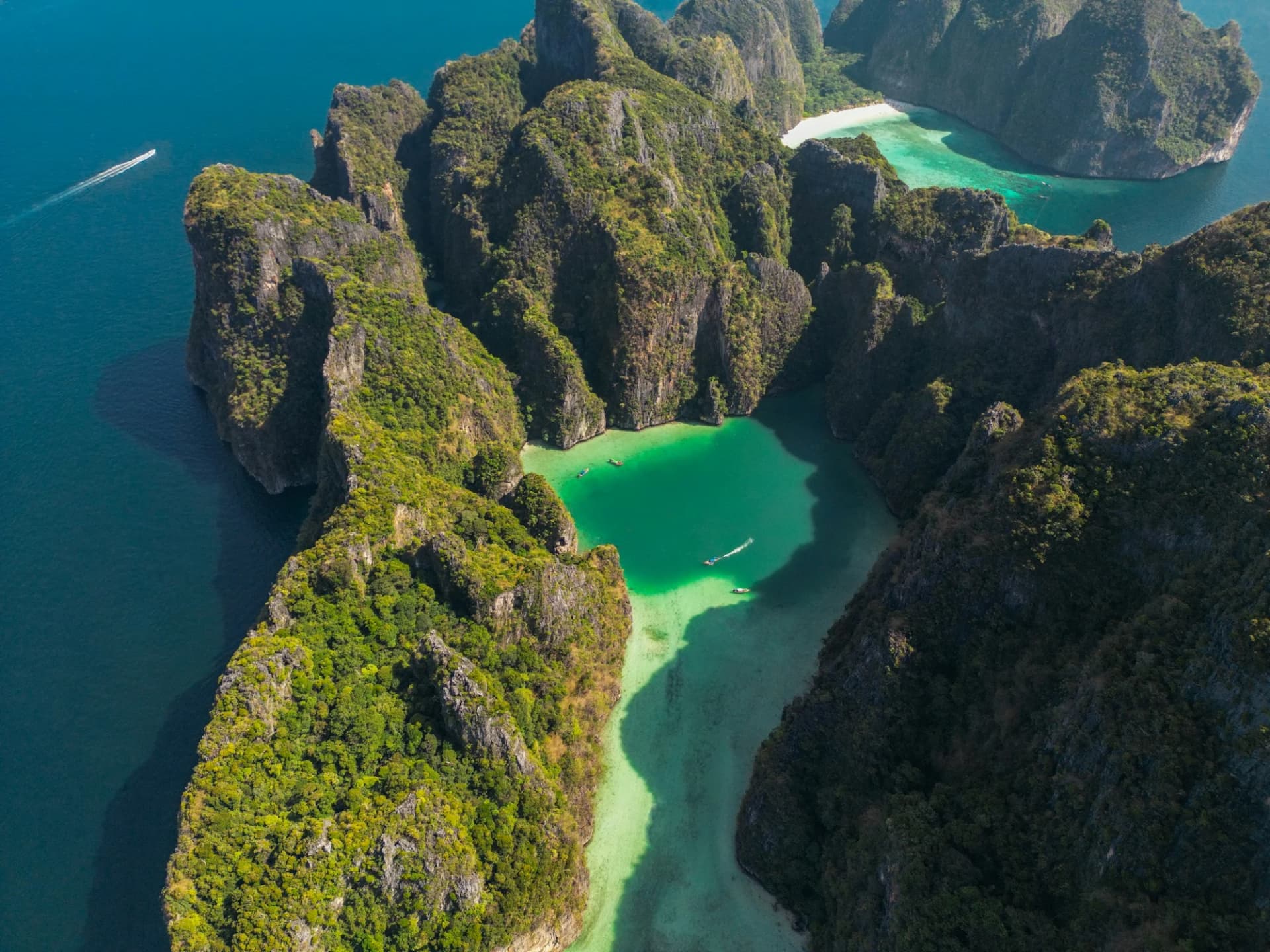 An aerial view of turquoise Pi Leh Lagoon and Maya Bay enclosed by towering green limestone cliffs on Ko Phi Phi Leh.
