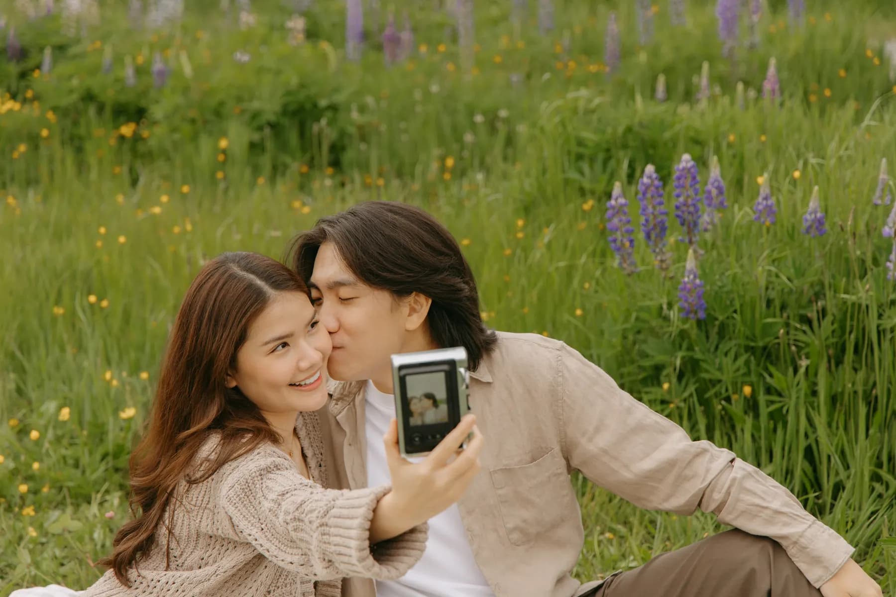 A kiss on the cheek while holding up an instax camera with their photo in it