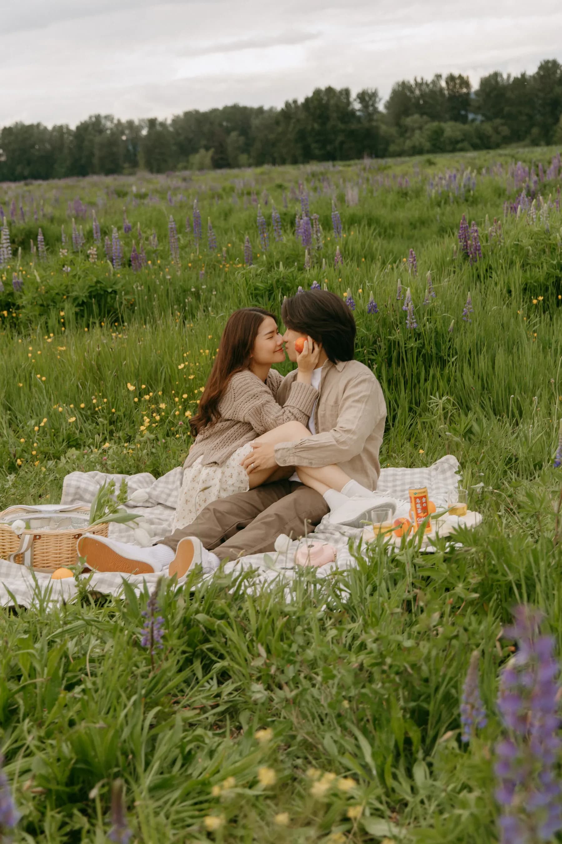 Sitting together in the grass, a peach held to Tony's cheek