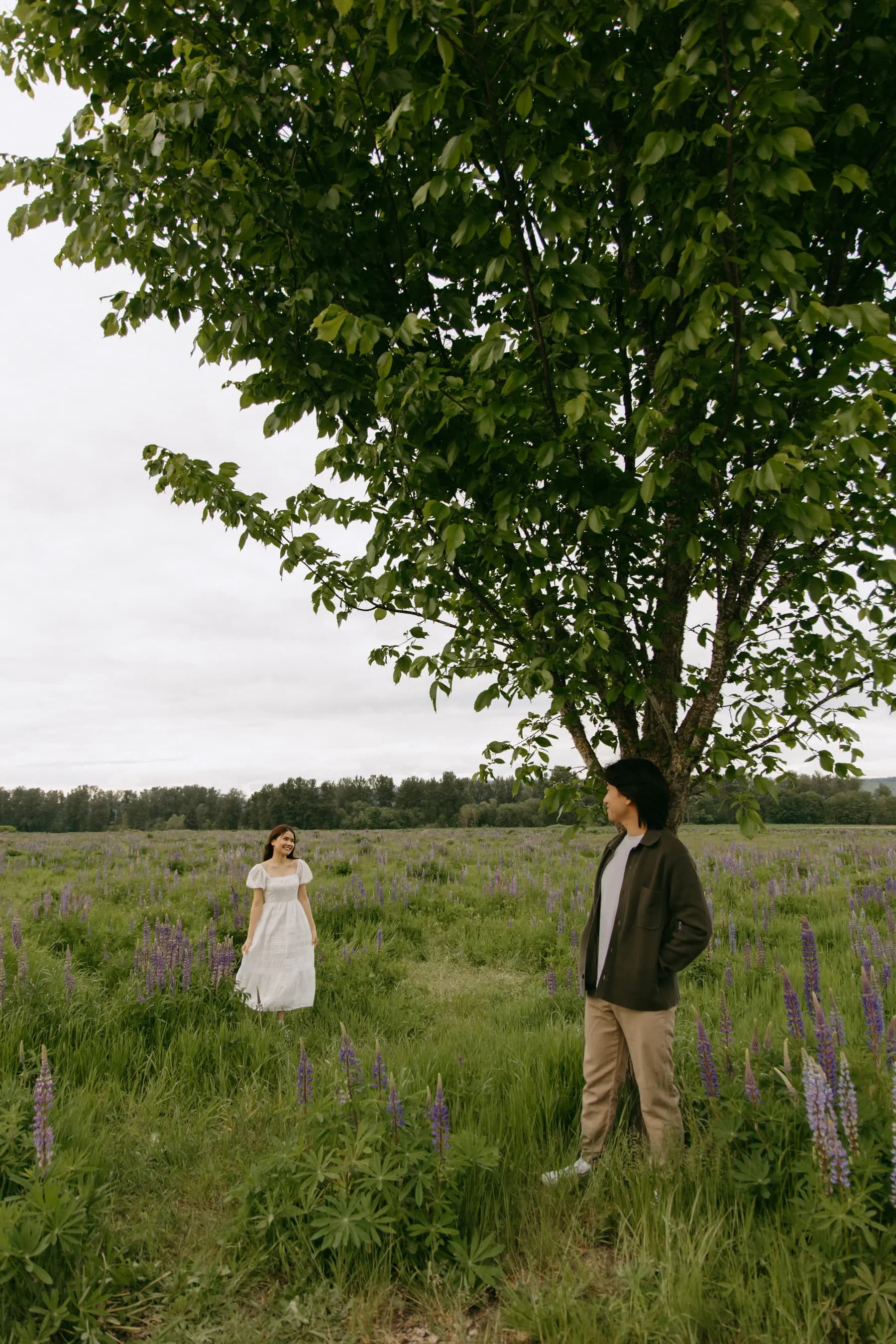 Standing apart in the meadow under one big tree, smiling at each other
