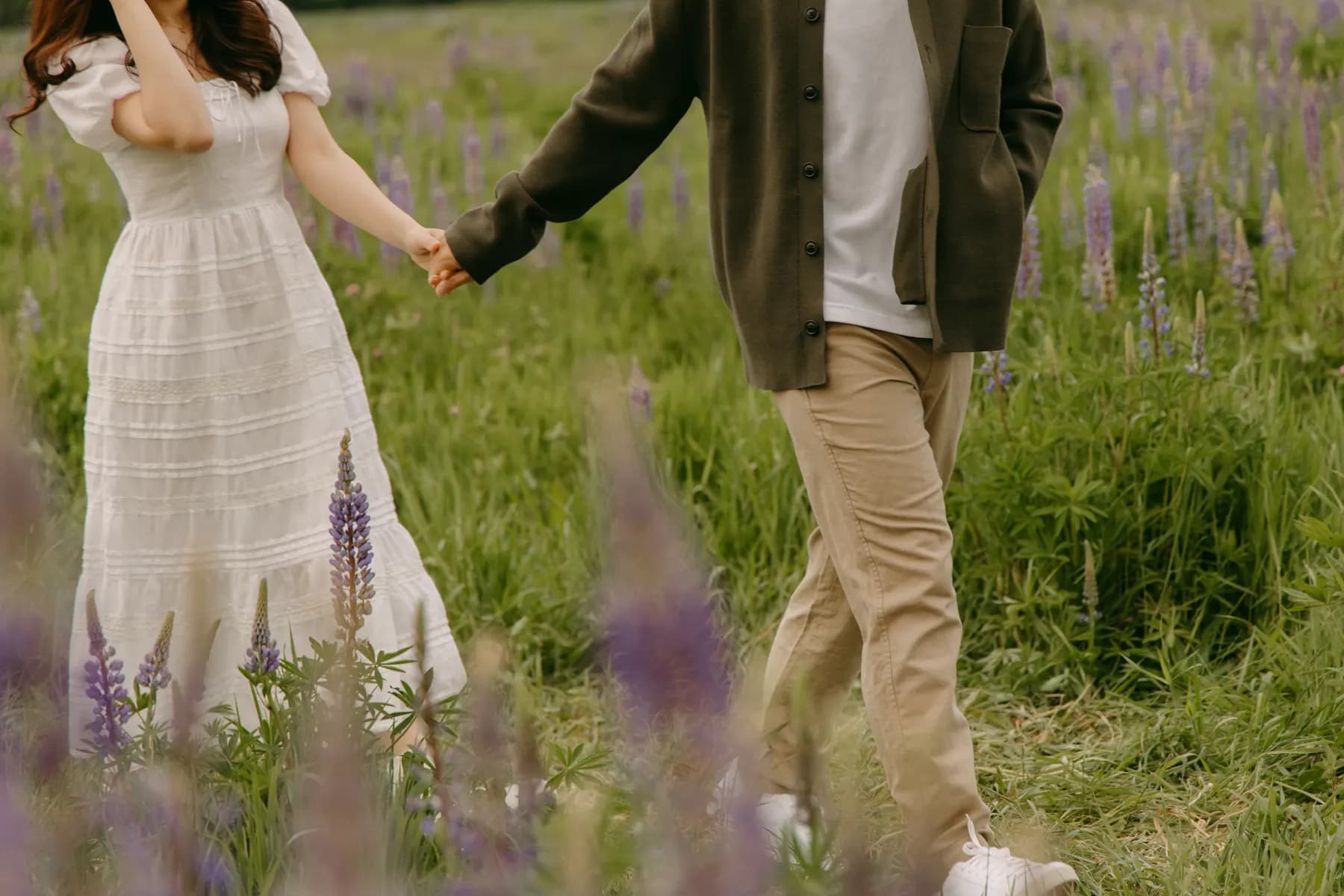 Hands clasped while walking through the lupines