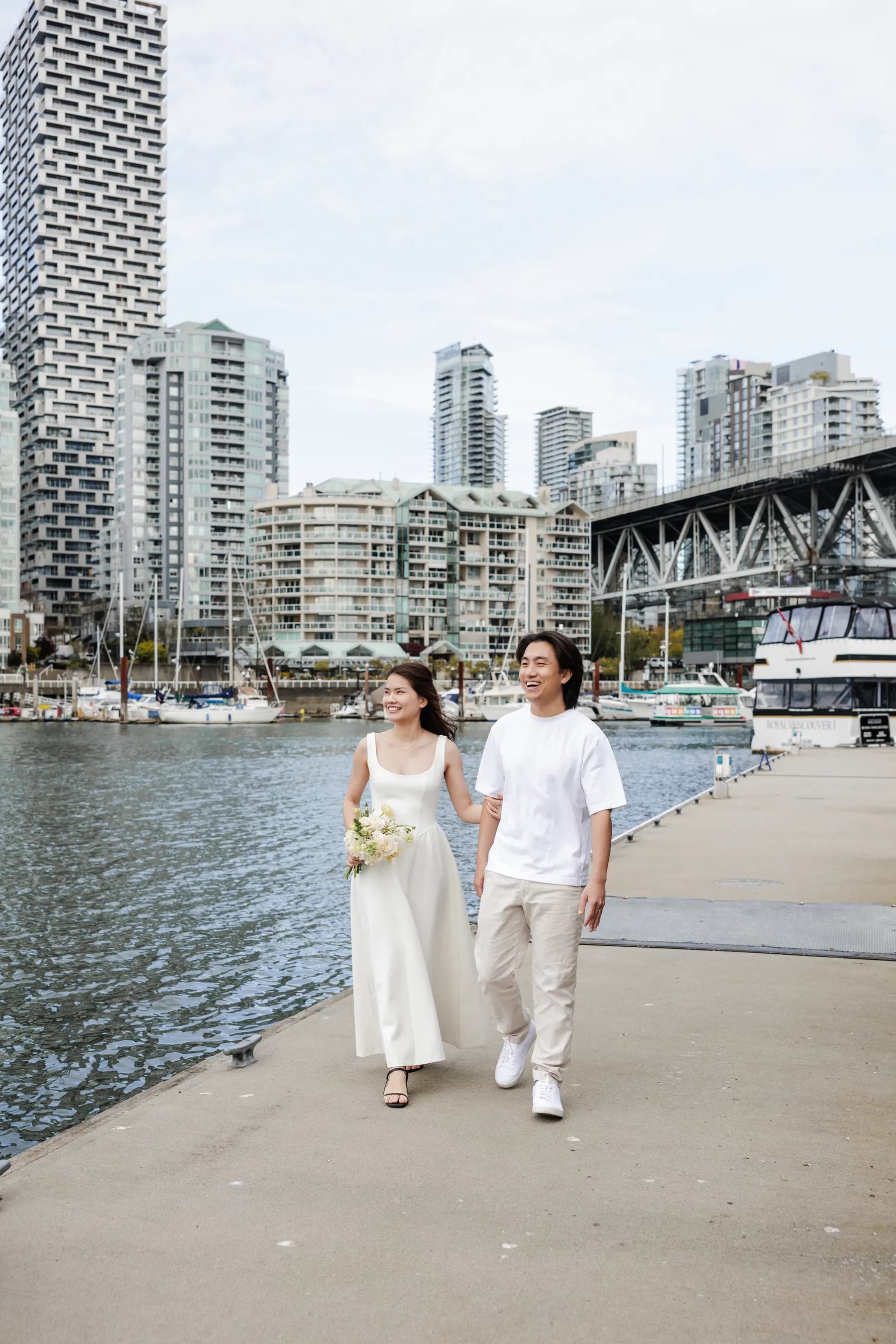 Walking along the False Creek boardwalk, bouquet in hand, Granville Bridge and the Vancouver skyline behind
