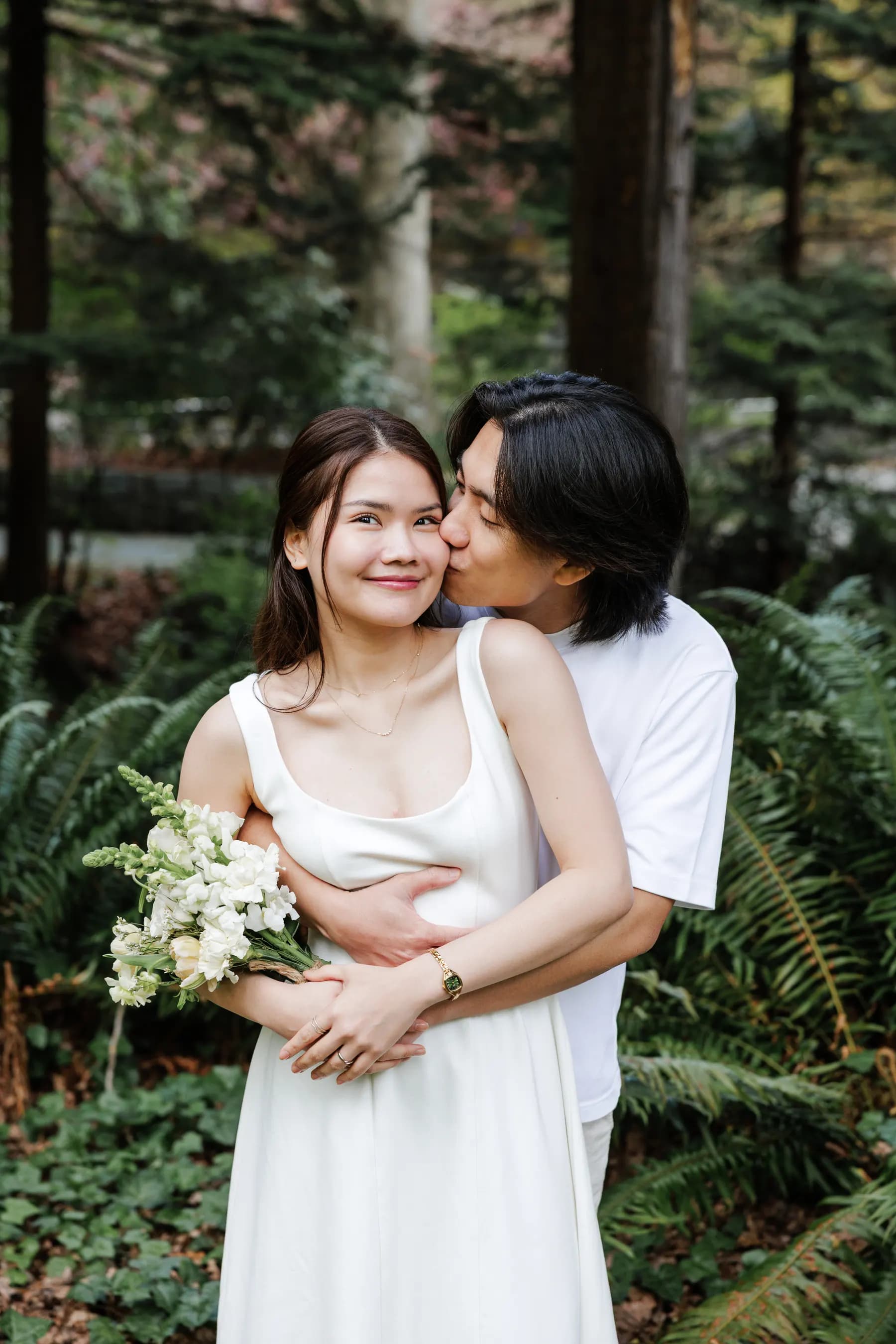 A kiss on the cheek among sword ferns and cedars